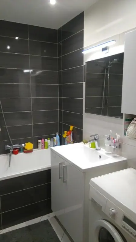 Malá koupelna s tmavým obkladem a vanou