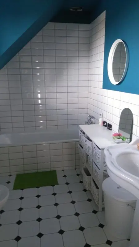 Podkrovní koupelna s bílým obkladem a šachovnicovou dlažbou