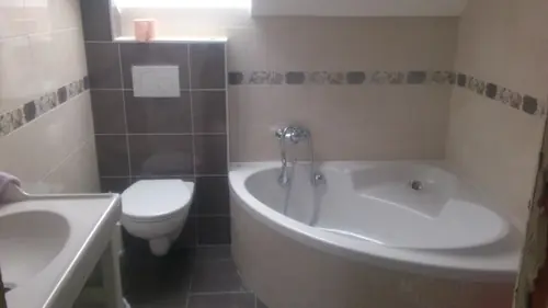 Rohová vana s hnědým obkladem a závěsným WC